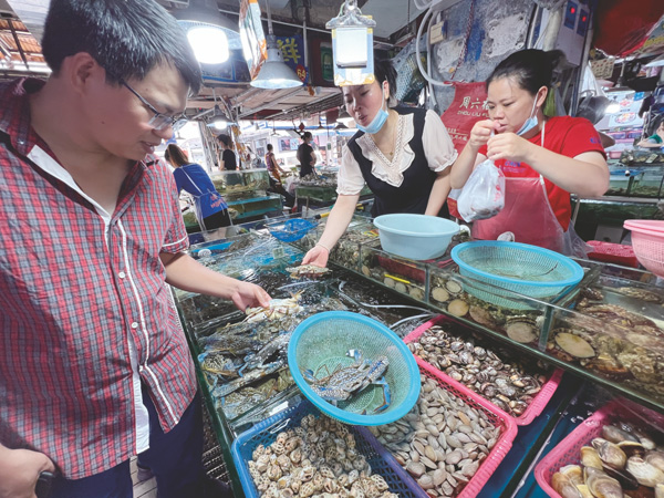  海鲜价格下降，市民在菜市场仔细挑选 。记者宋延康摄