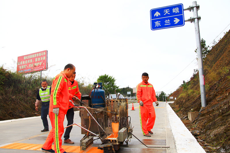 养路工人在国道243线凤山县境路段施划路面标线（河池公路发展中心 韦昌学  摄）