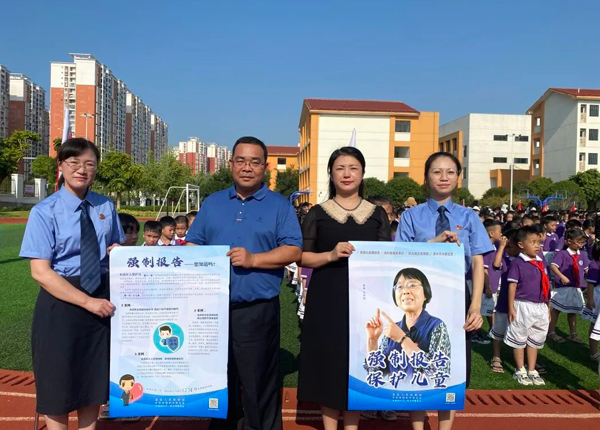 謝秋香法治副校長（左一）向學校贈送最高人民檢察院“強制報告制度”主題海報。