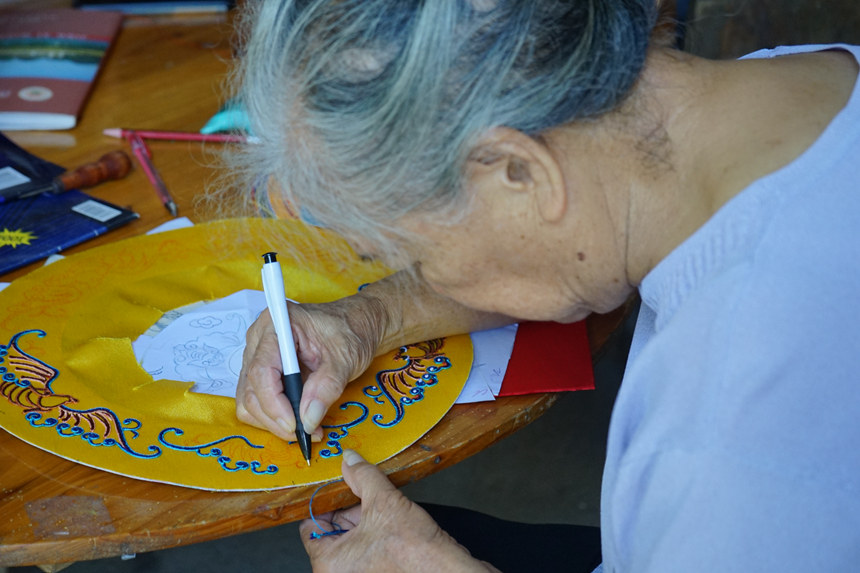 坐在家門口，80多歲的黃肖琴運用堆繡技藝設計、制作繡球。何善權攝