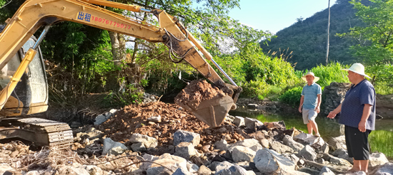 黨員組織挖掘機在修復吉田村水壩。