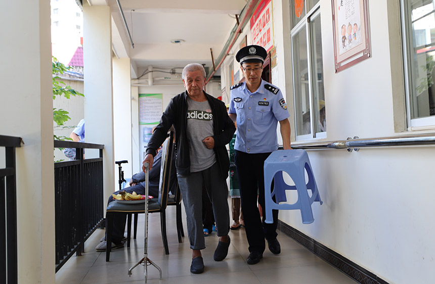 民警搀扶老人出门活动。