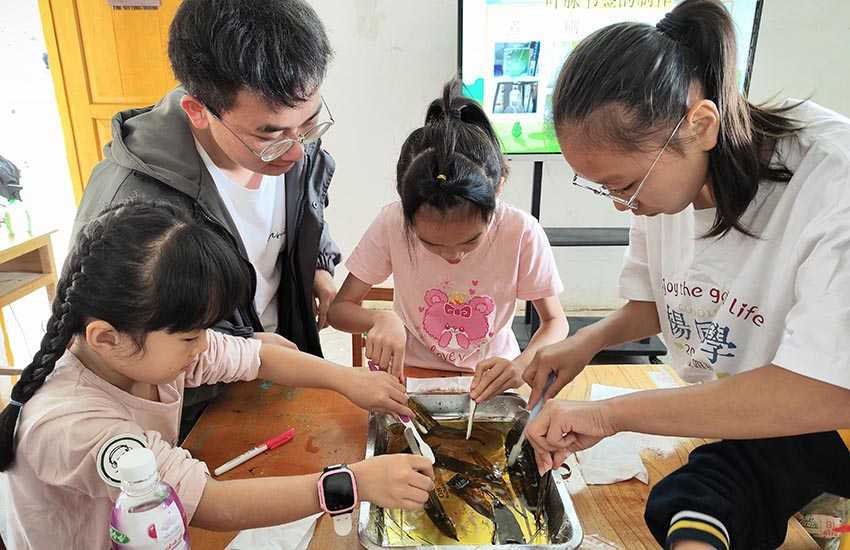 孩子们在农学院大学生帮助下动手制作芒果树叶书签。邓民胜摄