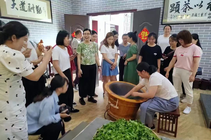 游客在故乡茶博园景区学习炒茶技艺