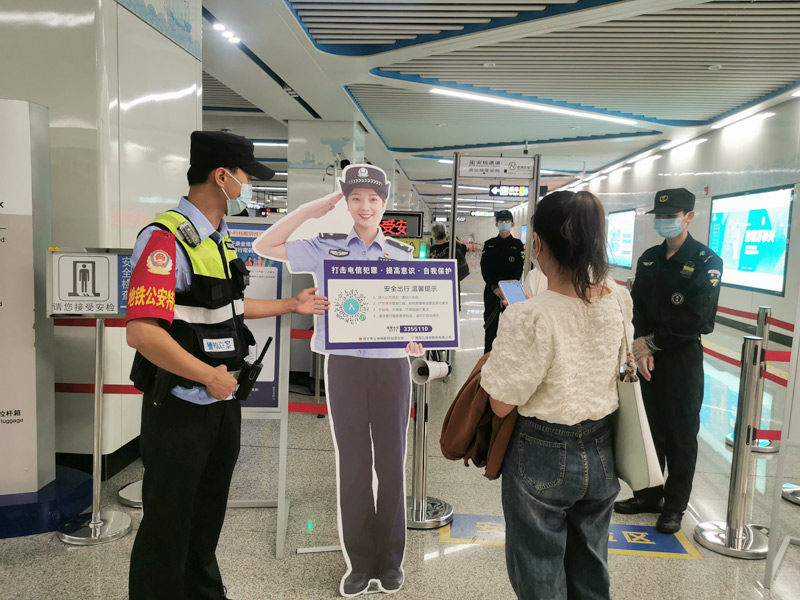 地鐵公安引導乘客掃描民警人形立牌二維碼進站。