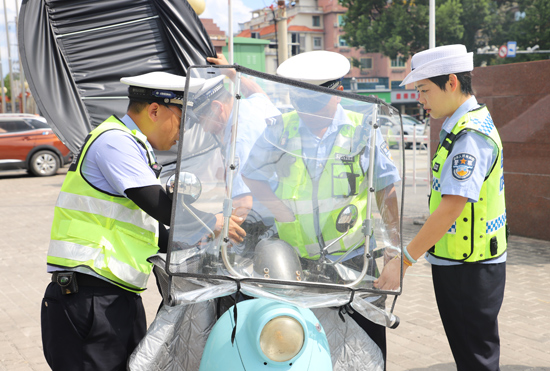 興安交警“拆傘小分隊”對非法加裝遮陽傘電動車現場進行處置。王欽攝