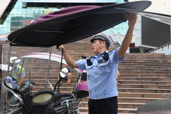 興安交警對非法加裝雨棚電動車現場進行拆除。粟桂艷攝