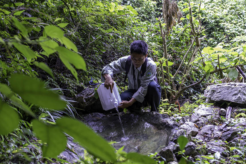 生态护林员在给白头叶猴饮水点加加水。