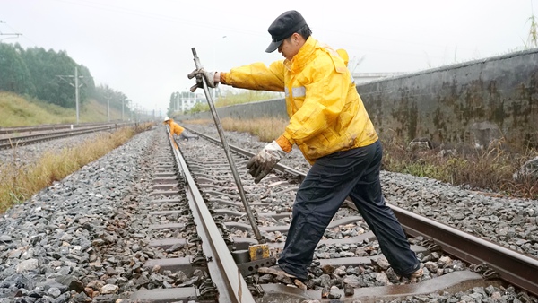 职工冒雨在线路上进行机械维修捣固作业。谭育俊摄