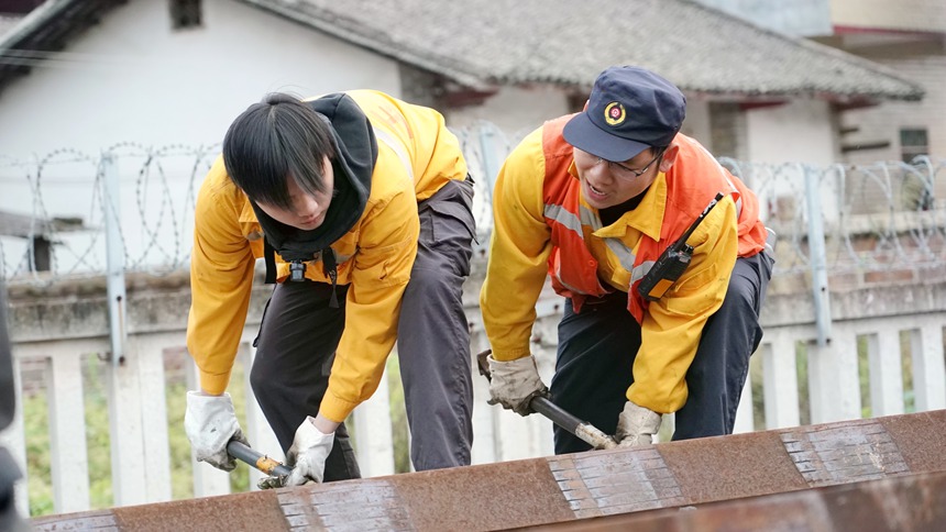 玉林工务段职工利用撬棍将钢轨一步步地拨上线路。谭育俊摄