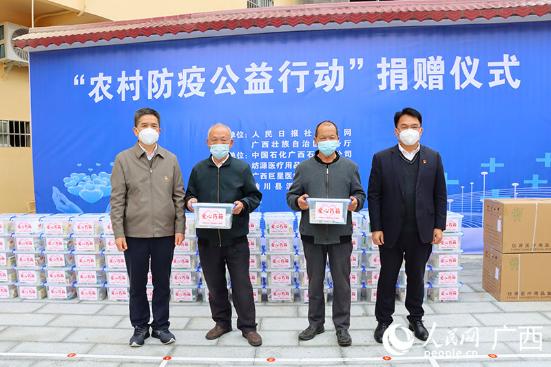 中国石化广西石油分公司三级协理员、工会副主席黄家华（左）和中国石化广西石油分公司总经理助理韦汉前（右）向村民发放防疫物资。人民网 付华周摄