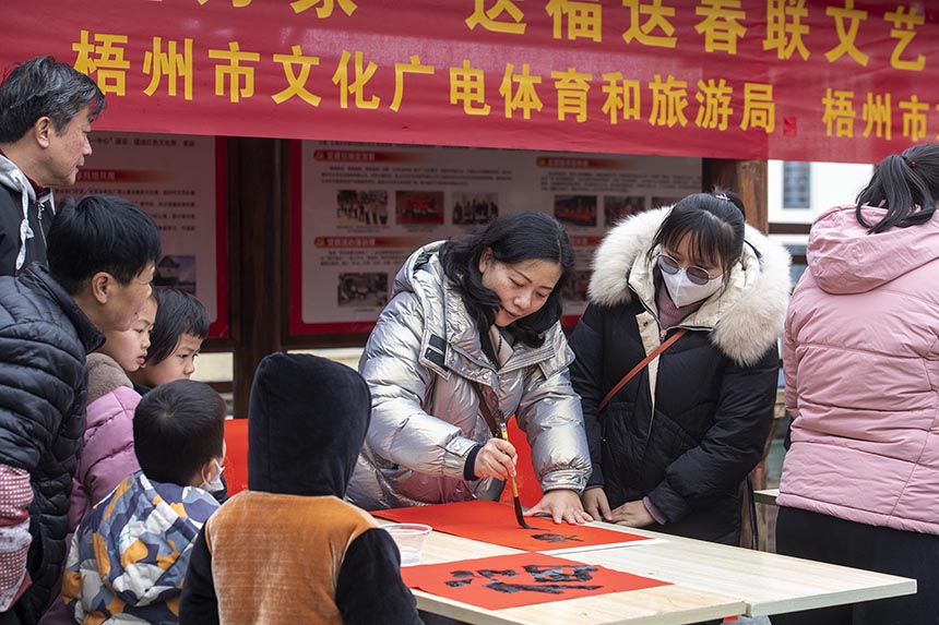 广西梧州市书法家协会志愿者正在给村民书写春联。何华文摄
