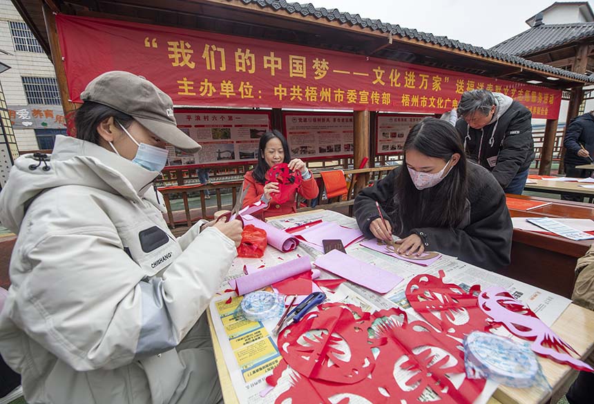 广西梧州市文艺志愿者开展迎春剪纸、写春联送福活动现场。何华文摄
