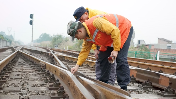 玉林工务段职工在雨中认真检查道岔岔心的几何参数，并做好标记。谭育俊摄