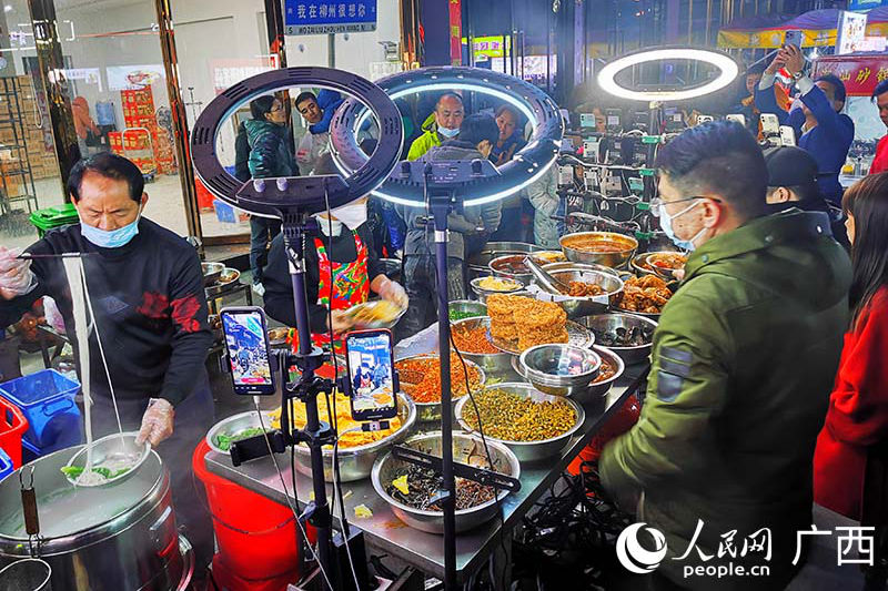 市民游客在柳州一家螺螄粉攤前排隊嗦粉。人民網 付華周攝.jpg