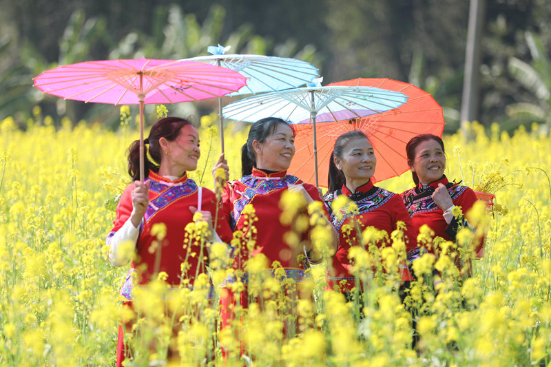 身着民族服饰的游客在油菜花田中唱歌打卡。东兰县融媒体中心供图