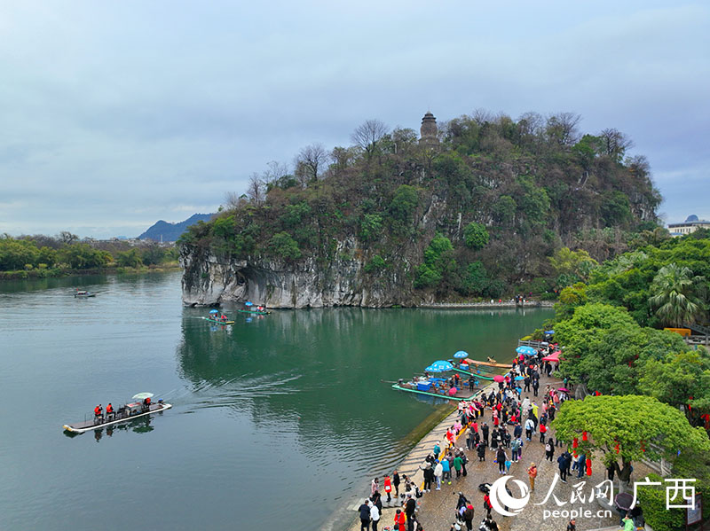 人们乘坐竹排，在漓江上欣赏象鼻山美景。人民网 付华周摄
