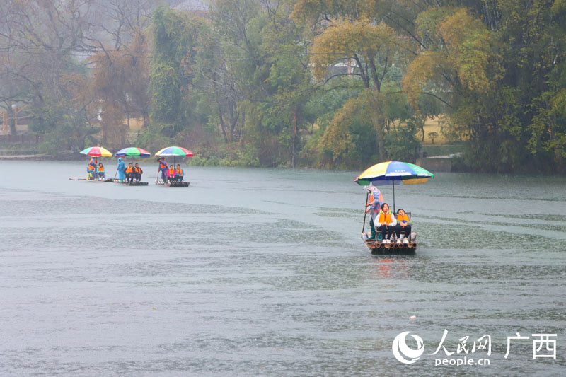 人們雨中乘坐竹筏欣賞遇龍河美景。人民網 付華周攝