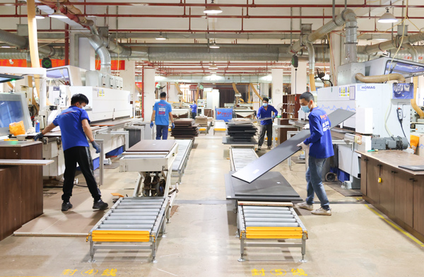 广西爱阁工房家居有限责任公司生产车间里，工人们忙着作业。