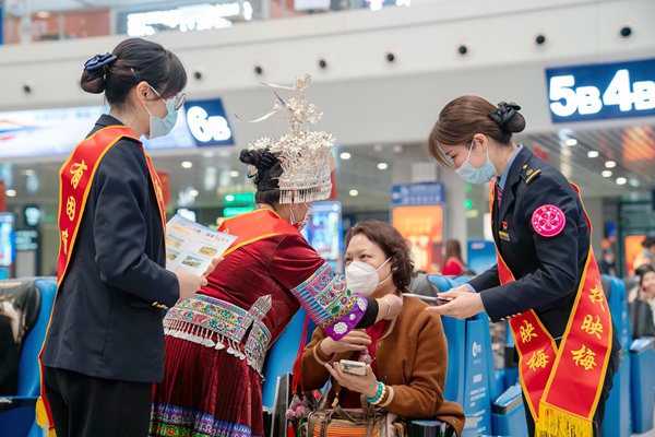 唐巧英正在为旅客佩戴苗族特色香囊。赵波摄