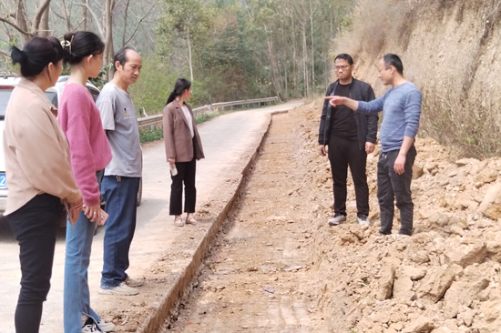 人大代表卢江明（右一）陪同镇政府考察组实地查看产业道路拓宽项目实施情况。