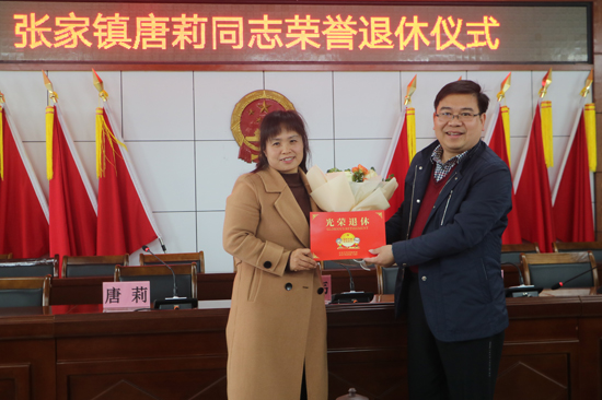 平乐县张家镇党委书记胡韦为退休干部唐莉颁发荣誉退休温馨卡。唐当彬摄