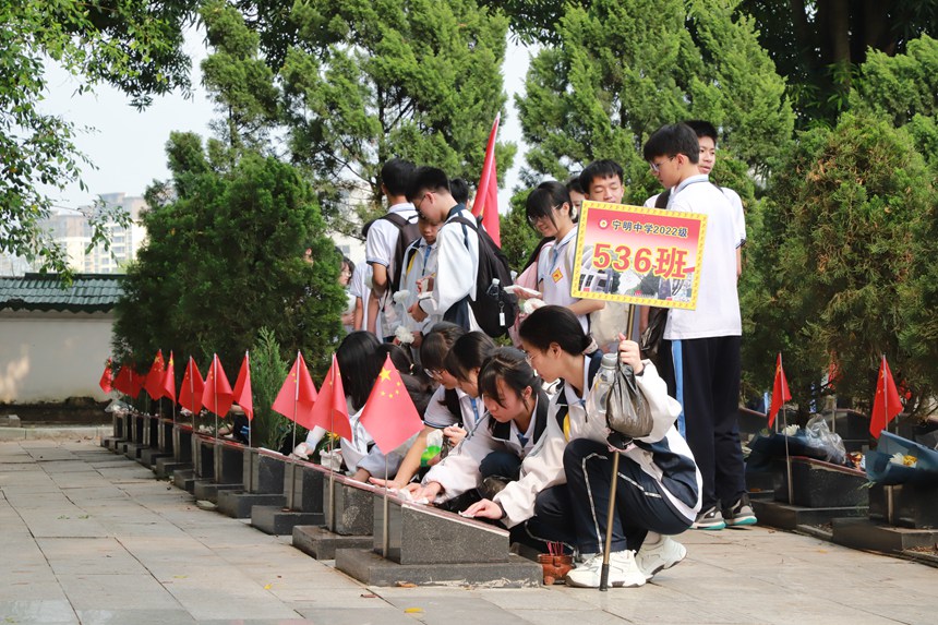 图为学生在擦拭墓碑