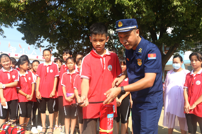 钟山镇第八小学学生在消防员指导下学习灭火器使用方法。廖超文摄