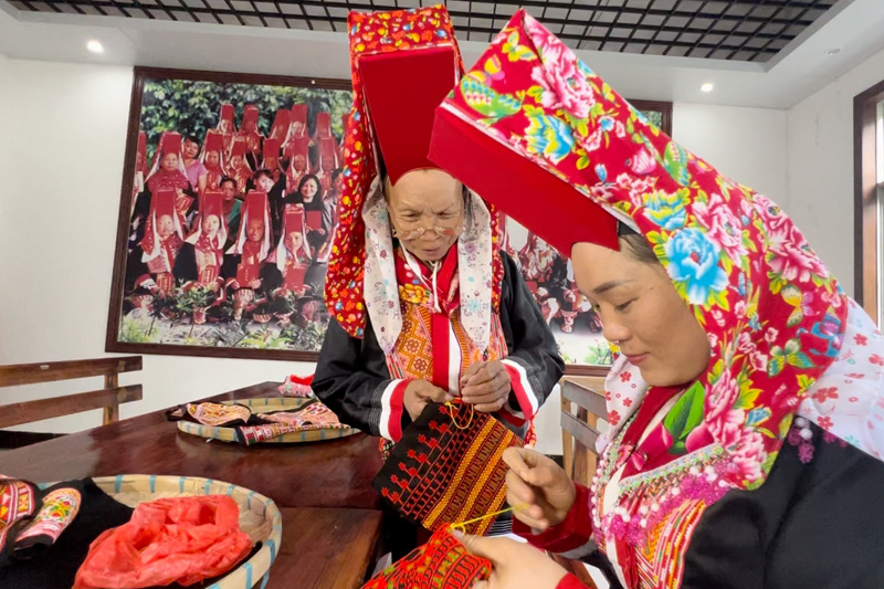 自治区级大板瑶服饰代表性传承人邓有芬正在向该村大板瑶姐妹邓福燕传授刺绣手法。