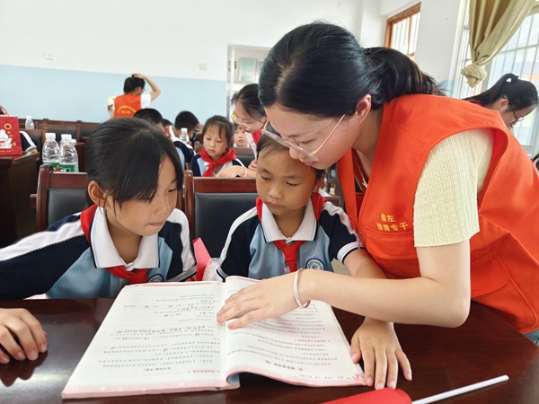 图为硕龙镇新时代文明实践所青年志愿者给留守儿童辅导作业 蓝丽利 摄