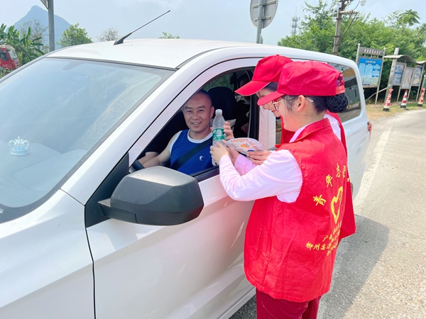 图为柳江分公司员工向过往司乘赠送文创产品与矿泉水