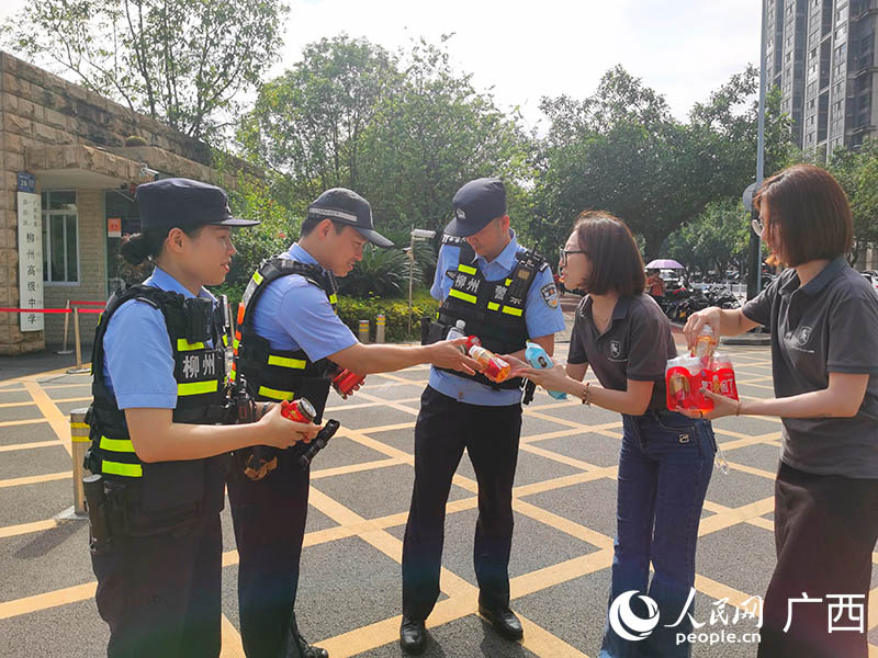 东风柳汽爱心送考车队工作人员向执勤民警赠送清凉饮料。人民网 付华周摄