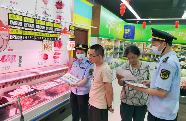 北海市铁山港区市场监管局工作人员向消费者宣传北海创建国家食品安全示范城市的相关内容和成效。