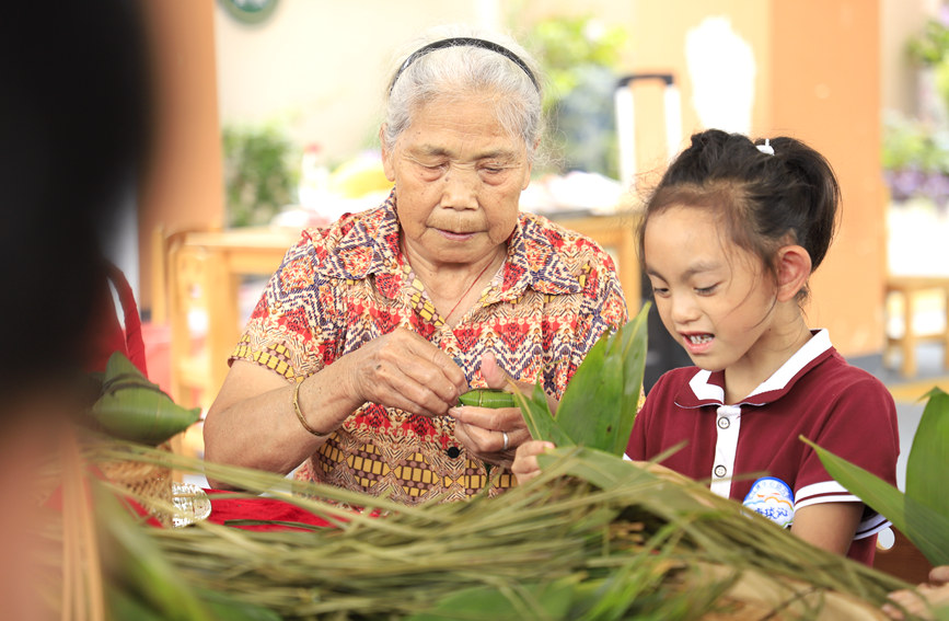 老人正在教孩子们包粽子。