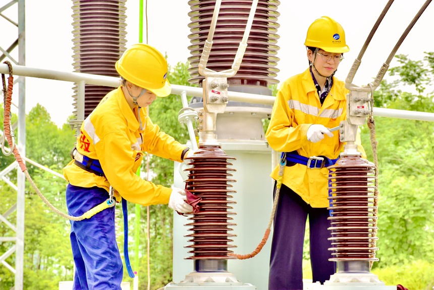 青年職工對變壓器絕緣套管擦拭和禁固線夾。 黃海源攝