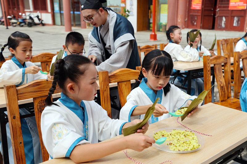 在国学讲堂上，小朋友们在学习包粽子。罗莹摄