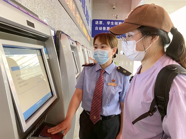 南宁东站工作人员协助旅客在自动售票机办理业务。于莉摄