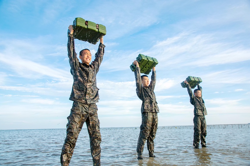 武警官兵在海水中进行负重训练。