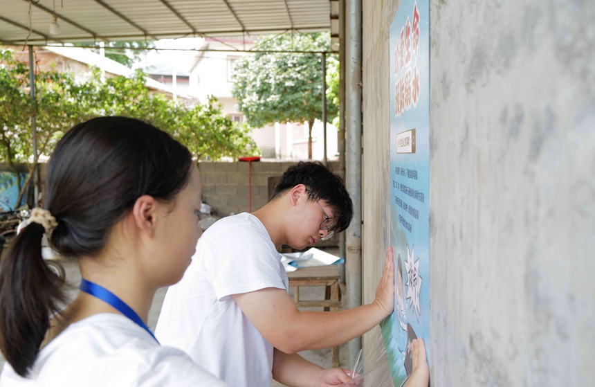 志愿者在乡村张贴防溺水安全教育海报 沙远峰摄