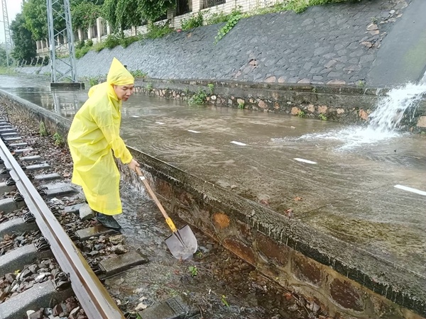 玉林工务段职工冒雨清理线路堵塞的排水设备，确保线路排水通畅。廖成摄
