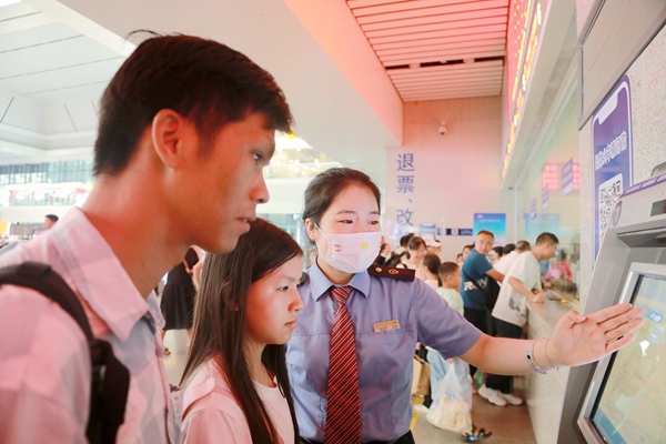 南宁东站工作人员引导旅客在自助售票机上办理改签业务。于莉摄