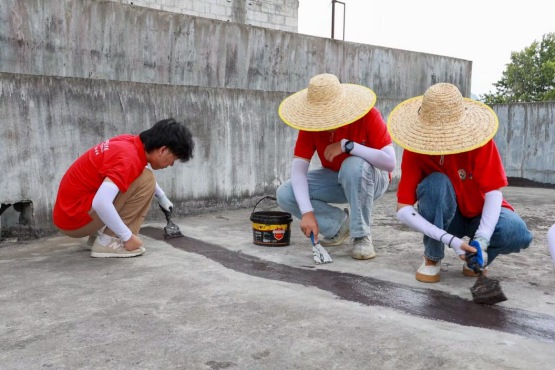 实践团成员在裂缝处涂抹防水涂料
