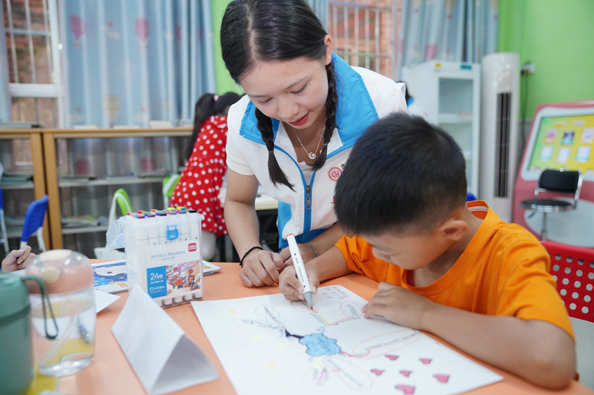 大学生志愿者在指导孩子们绘画。