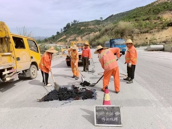 养护工人在烈日下修补路面坑槽