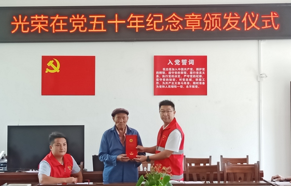 黄何华为在党五十年老党员颁发纪念章。右江民族医学院供图