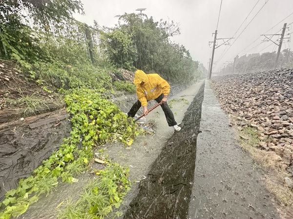 职工冒雨清理黎湛铁路两侧水沟。刘毅摄