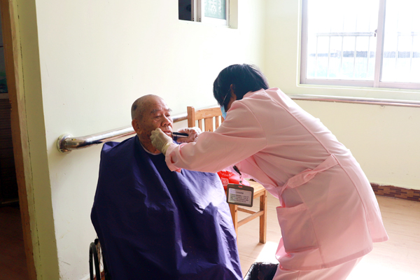 护工正在给老人刮胡子。黄颖摄
