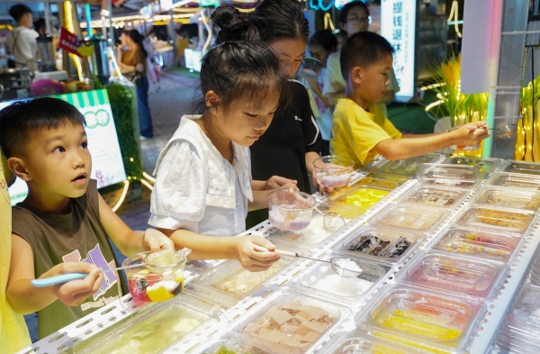 熒光夜市裡，孩子在挑選零食。港北區融媒體中心供圖
