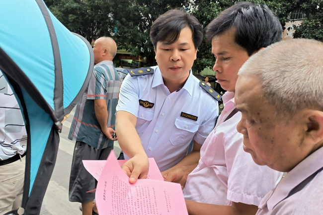 执法人员为社区群众发放普法宣传单。李琨宁摄