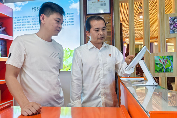 图为客户经理（右）指导何文科开展经营指导。韦炳得摄